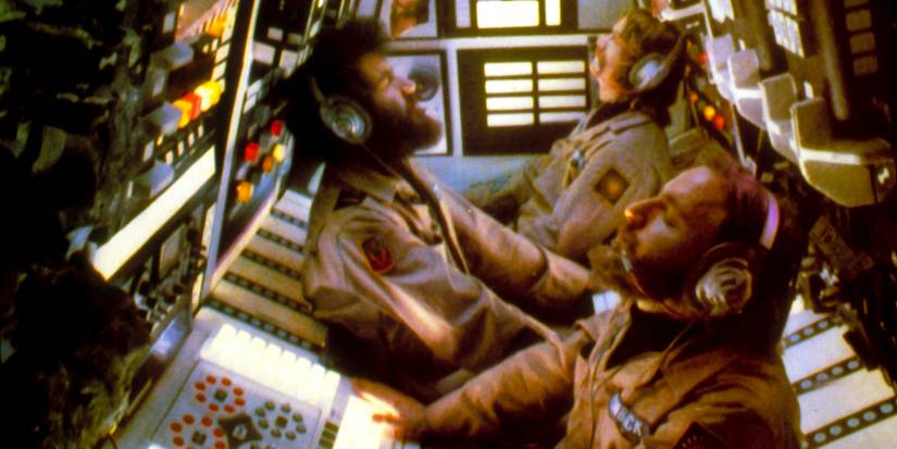 The crew of a spaceship sit in the tight confines of the control room.