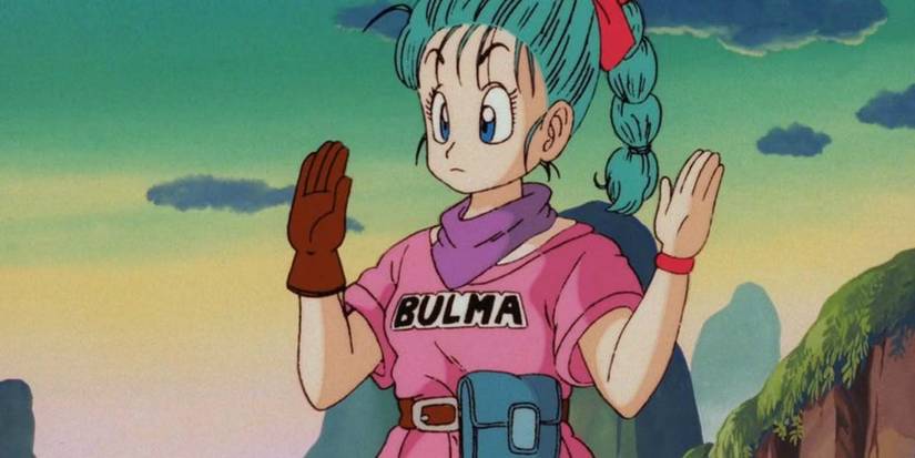 Bulma Briefs, wearing a pink shirt with her name on the front, a purple bandana around her neck, and a brown glove on one hand, holding up both her hands with a blank expression looking ahead in Dragon Ball