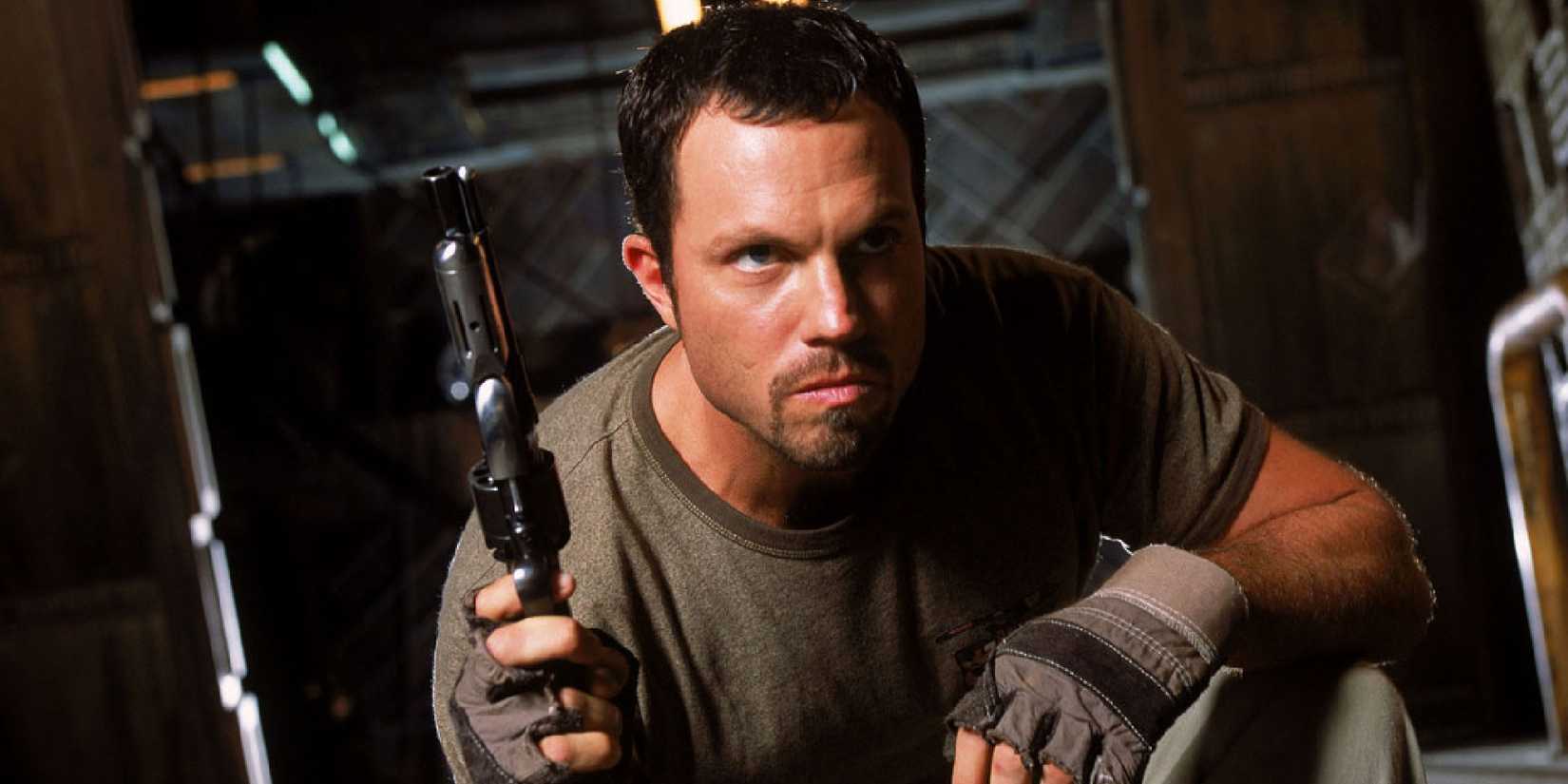Jayne crouches down and holds a weapon in 'Firefly.'