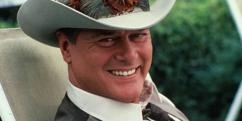 J.R. Ewing in a cowboy hat, sitting and looking at something off camera in Dallas.