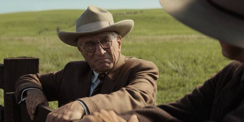 Robert De Niro as William Hale, leaning on a fence, in Killers of the Flower Moon