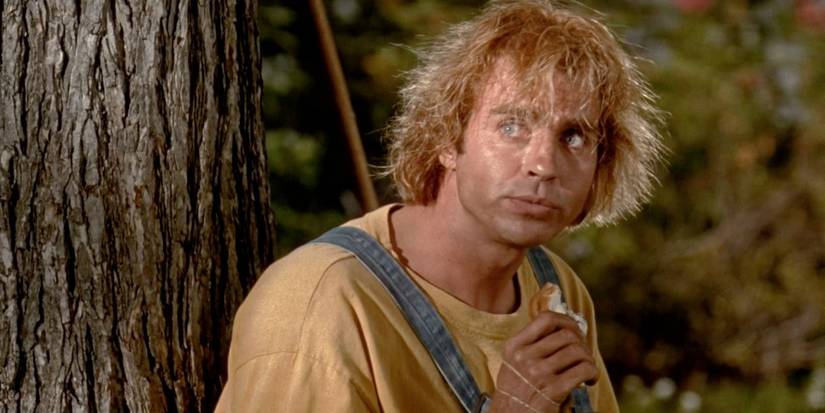 Jeff Fahey as Jobe, sitting by a tree and eating a sandwich in The Lawnmower Man