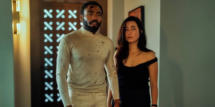 Maya Erskine and Donald Glover looking disheveled after a fight and staring ahead in Mr. & Mrs. Smith.