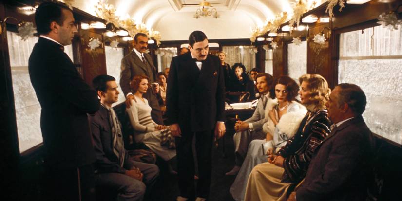 The cast in period costumes sit in a train car with tension in the air in Murder on the Orient Express, 1974.