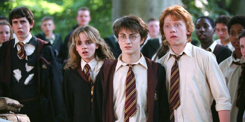 Harry, Ron, and Hermione look stunned in a crowd at school in Prisoner of Azkaban.