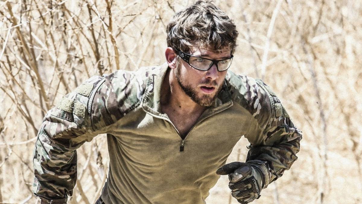 Max Thieriot as Clay Spenser, running through branches and wearing protective glasses in SEAL Team
