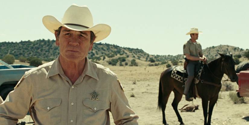 O xerife Bell (Tommy Lee Jones) em pé em um deserto perto de um oficial em 'No Country for Old Men'