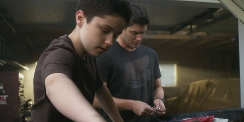 Dean Winchester (Jensen Ackles) teaches Ben Braeden (Nicholas Elia) how to fix a car on 'Supernatural'