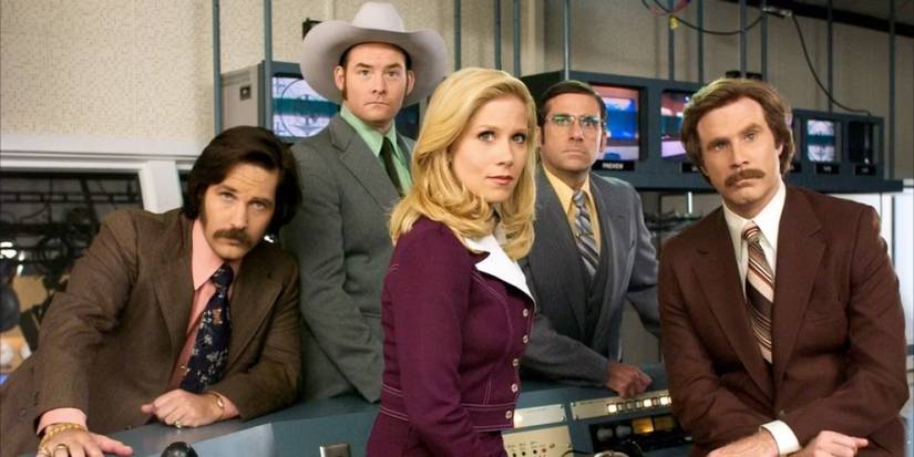 Five people pose in a photo in slick suits and polished looks in what appears to be a television studio