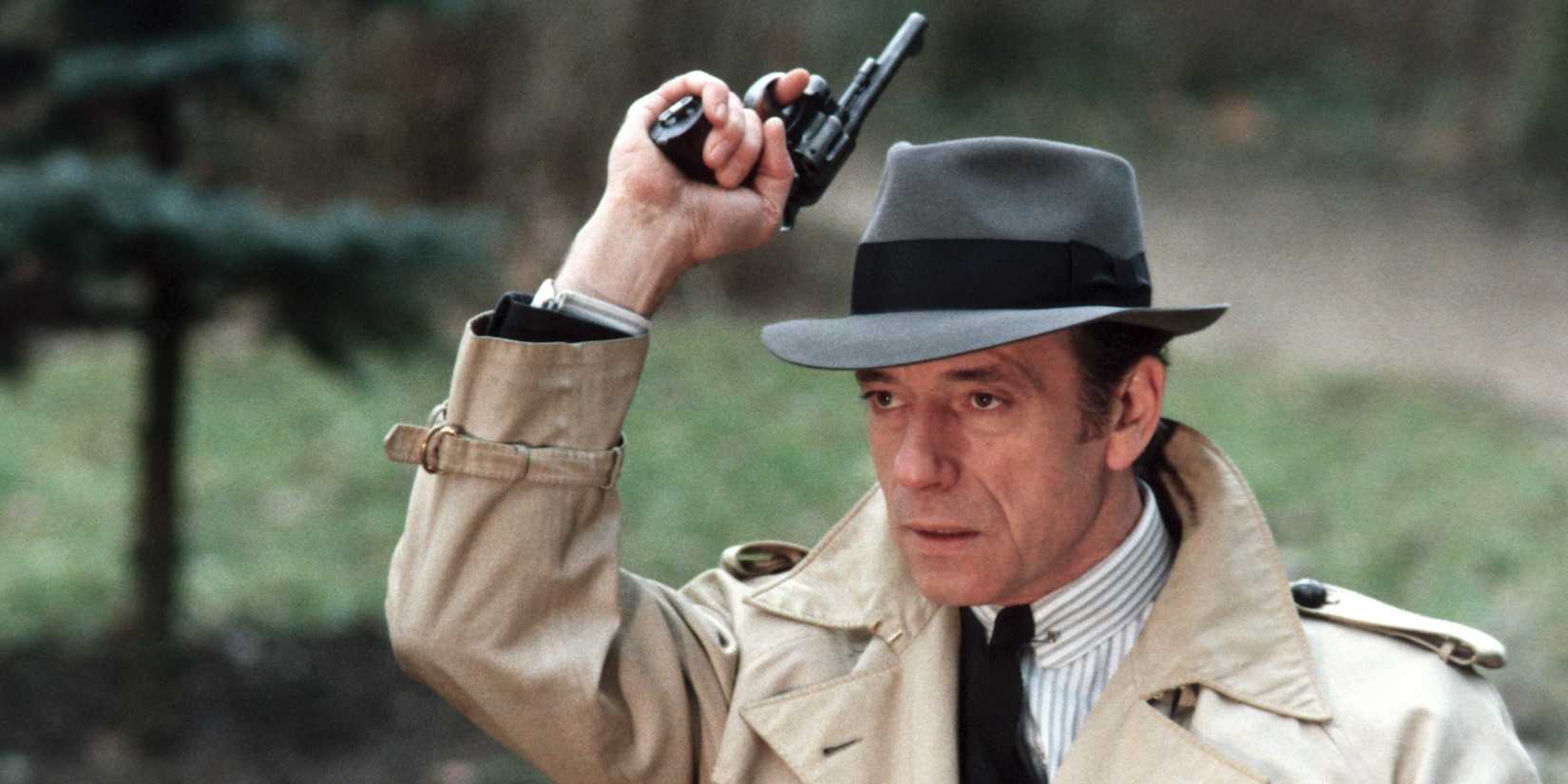 André Bourvil as Inspector Mattei in a trenchcoat holding a gun in the air in The Red Circle, AKA Le Cercle Rouge