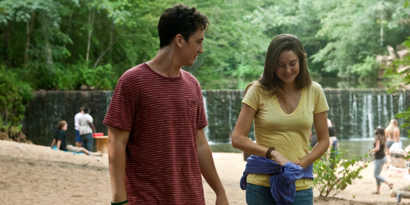 Sutter (Miles Teller) and Aimee (Shailene Woodley) smiling and walking by the lake in The Spectacular Now