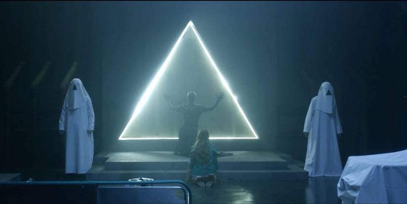 People in awe of a triangle of light in The Void (2016).