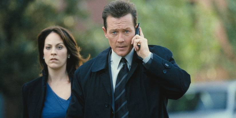 Annabeth Gish walks behind Robert Patrick on the phone in The X-Files