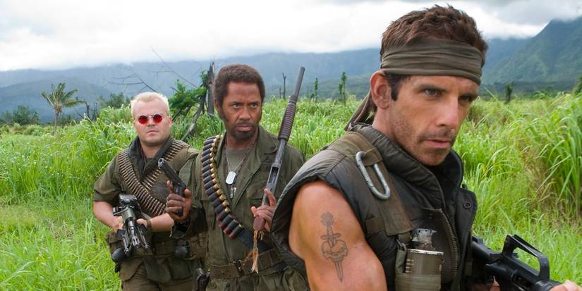 Jack Black, Robert Downey Jr and Ben Stiller dressed as soldiers walk through tall grass in Tropic Thunder.