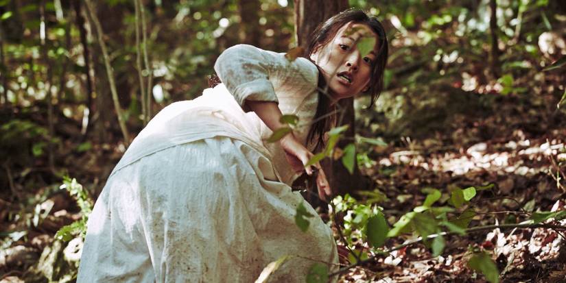 Chun Woo-hee wearing a white dress, crawling through the woods afraid in The Wailing