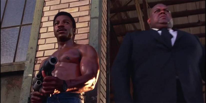 Carl Weathers in Action Jackson holding a gun while shirtless.