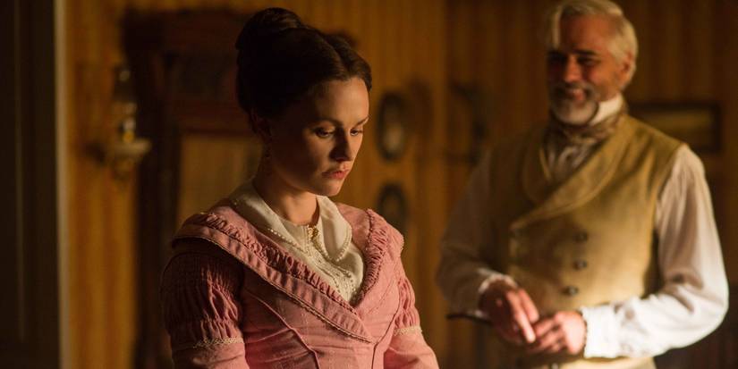 Nancy Montgomery, played by Anna Paquin, looking down with Thomas Kinnear, played by Paul Gross, in the background to the right smiling at her, in Alias Grace