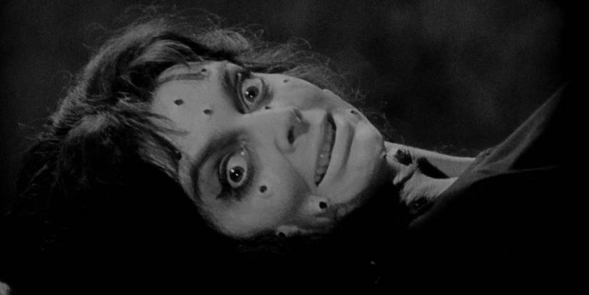 A woman with marks on her face smiling creepily in Black-Sunday