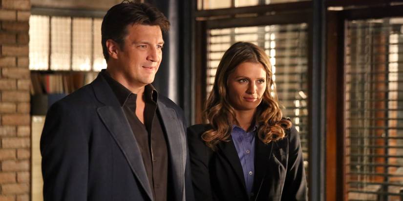 Nathan Fillion as Richard Castle and Stana Katic as Kate Beckett standing together in a police precint in Castle