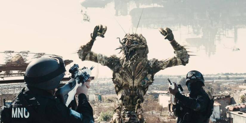 Soldiers aim their guns at an alien with its arms up in District 9.  