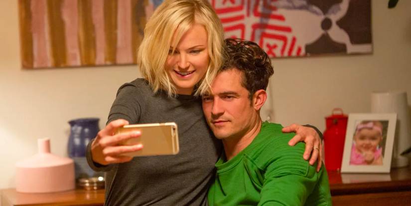 A woman sits with her boyfriend as the happy couple pose for a selfie in a living room.