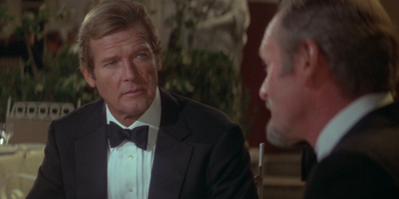 James Bond (Roger Moore) sits opposite Aristotle Kristatos (Julian Glover) wearing a tuxedo.