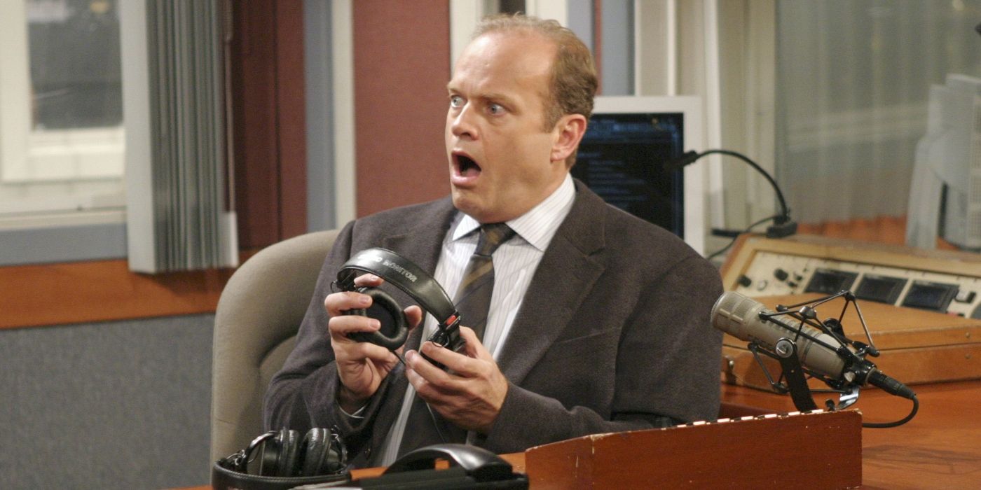 Kelsey Grammer as Frasier Crane, sitting at his desk holding a pair of headphones and looking shocked on Frasier