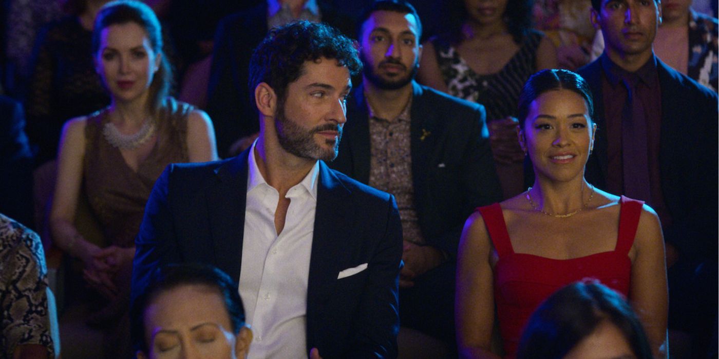 Gina Rodriguez wearing a red dress smiling while Tom Ellis looks at her in 'Players'