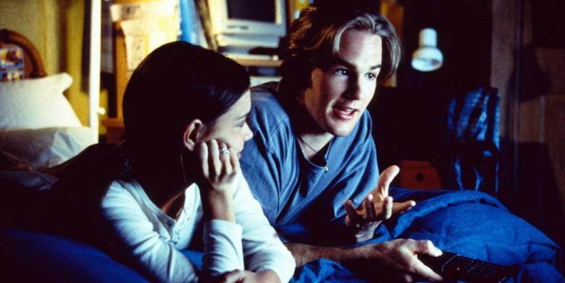 Katie Holmes and James Van Der Beek talking on a bed in Dawson's Creek