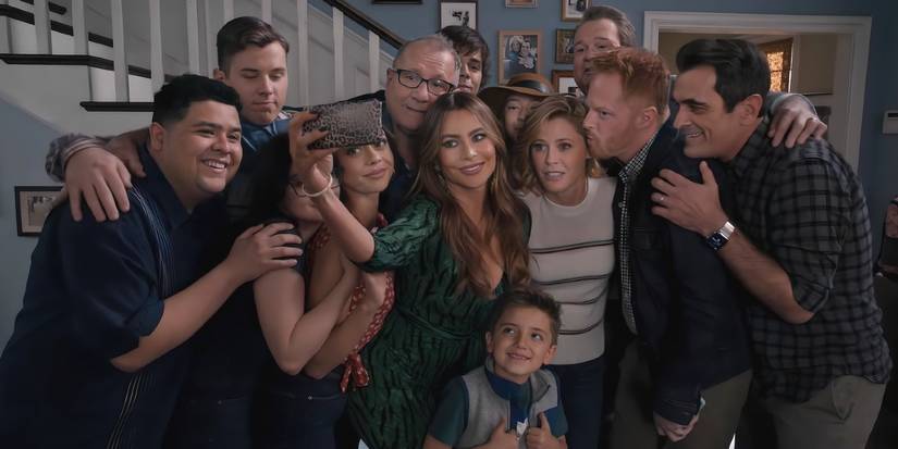 The main characters from Modern Family embracing in a living room.