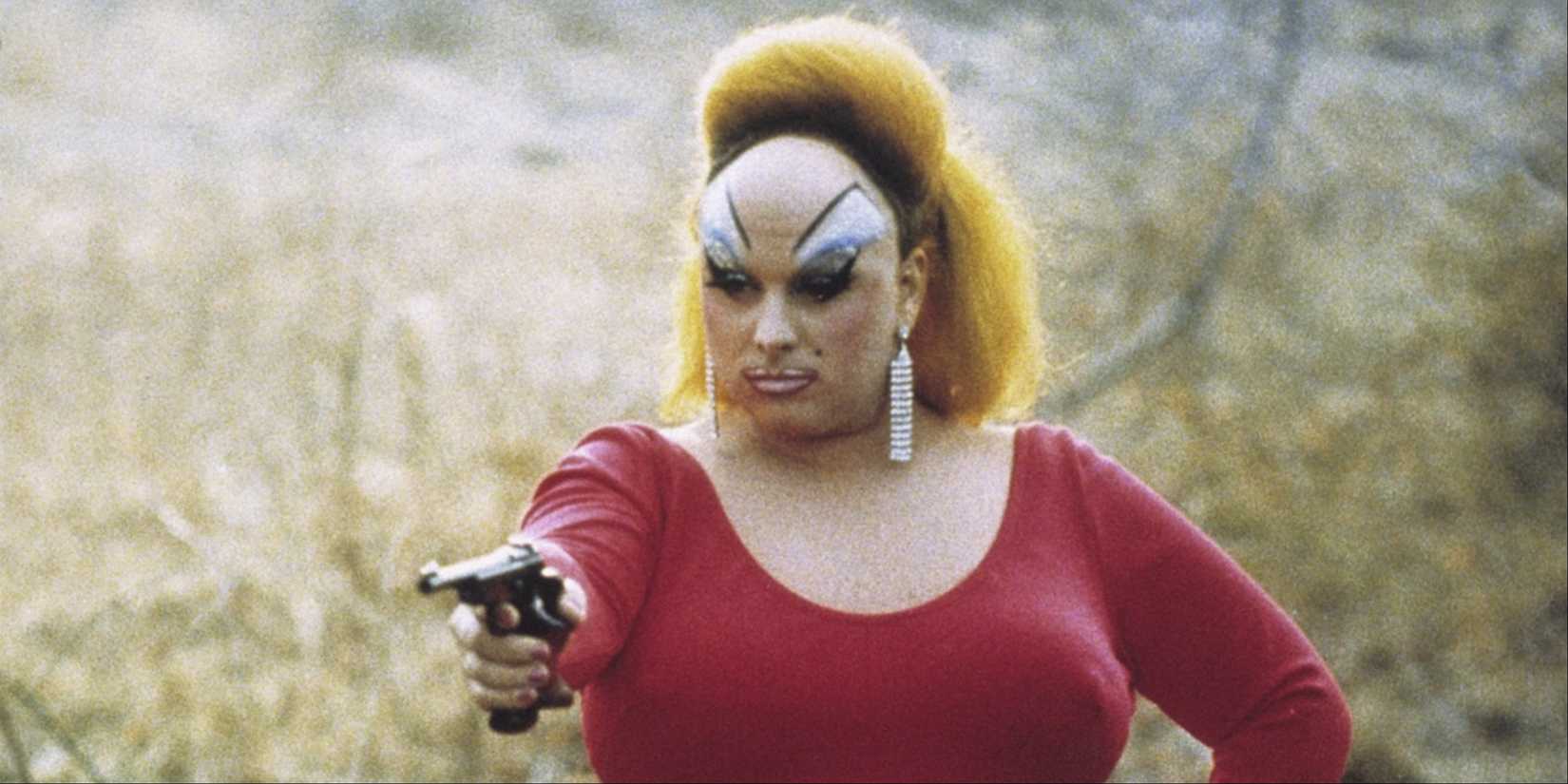 Divine aiming a gun at something off-camera in Pink Flamingos.