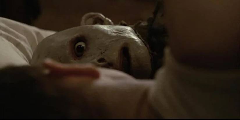 Monster in the bed looking at a person with their back to the camera in Possum 2018