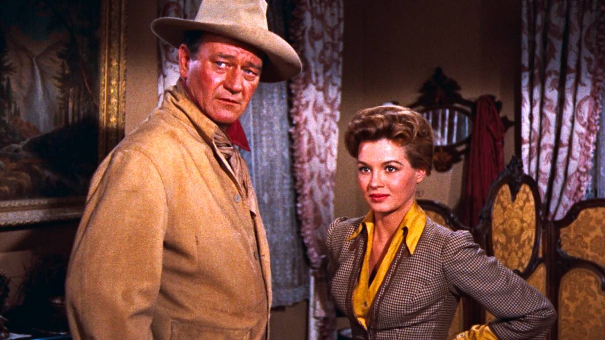 John T. Chance (John Wayne) and Feathers (Angie Dickinson) stand in a hotel room of a saloon in 'Rio Bravo' (1959)