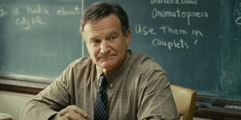 Lance Clayton, sitting at his desk in front of a blackboard in World's Greatest Dad