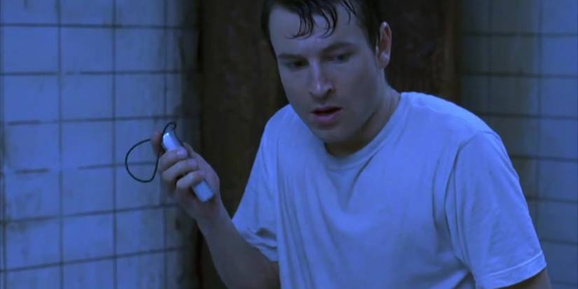 Adam, played by actor Leigh Whannell, holding a dictaphone in Saw.