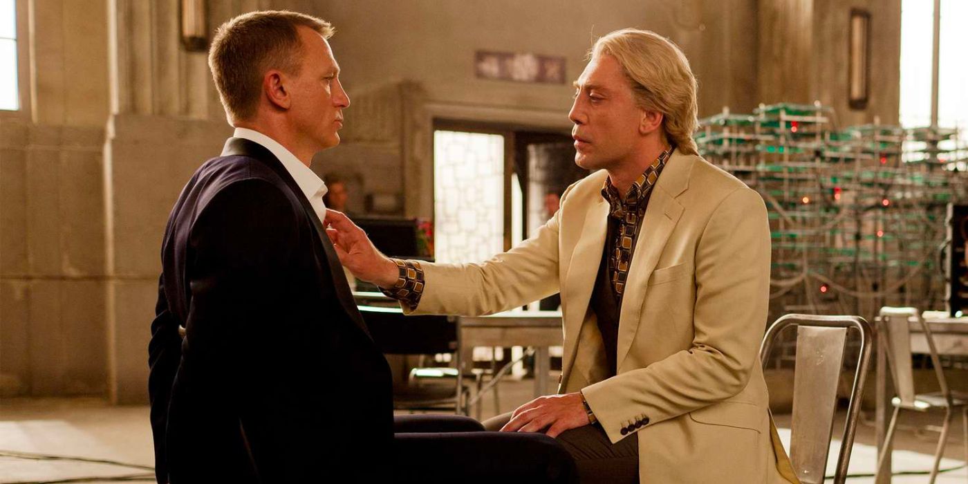 James Bond sits tied to a chair while Raoul Silva tenderly plays with his shirt collar.