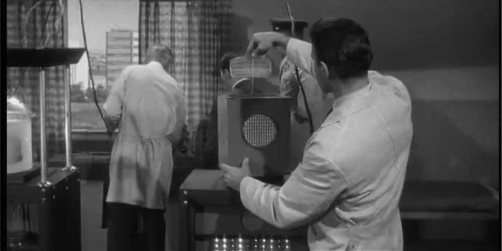 A man working on a machine while another is plugging it in Outer Limits