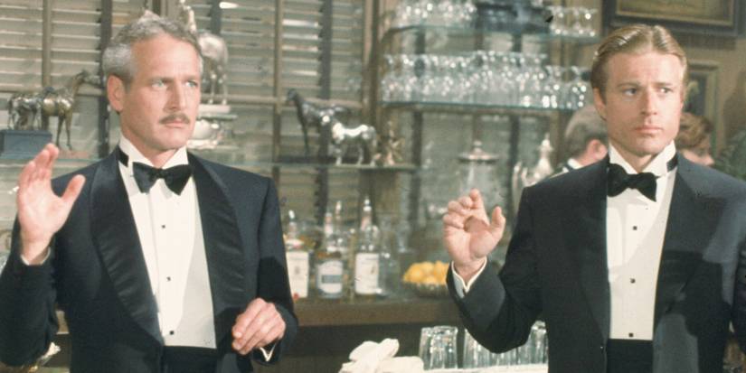 Paul Newman and Robert Redford as Henry and Johnny, standing in suits in front of a bar with their hands raised in The Sting