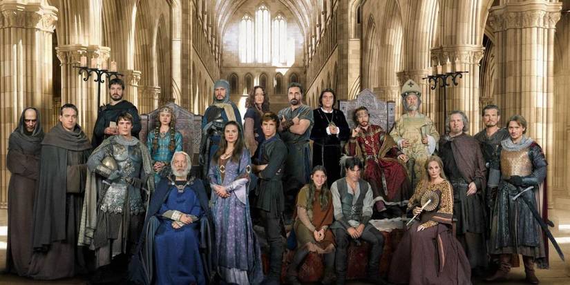 The cast of 'The Pillars of the Earth' pose for a photo with a cathedral backdrop.