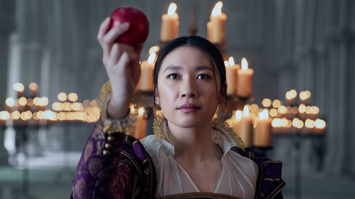 Jess Hong as Jin Cheng holding up an apple in a candlelit church in episode 103 of '3 Body Problem.'