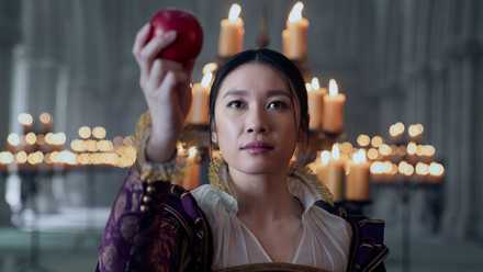 Jess Hong as Jin Cheng holding up an apple in a candlelit church in episode 103 of '3 Body Problem.'