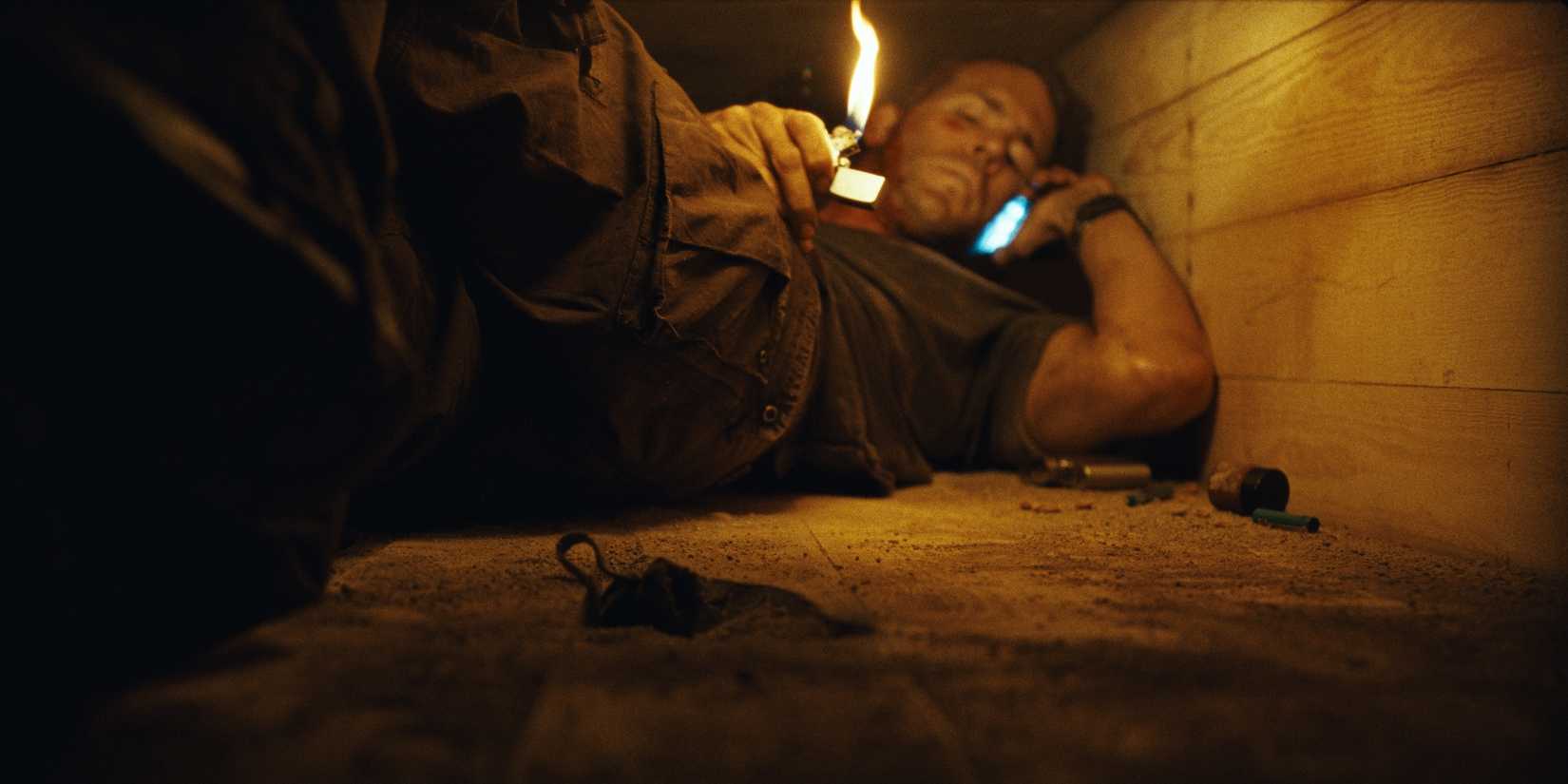 Ryan Reynolds as Paul Conroy talking on the phone while holding a lighter in Buried