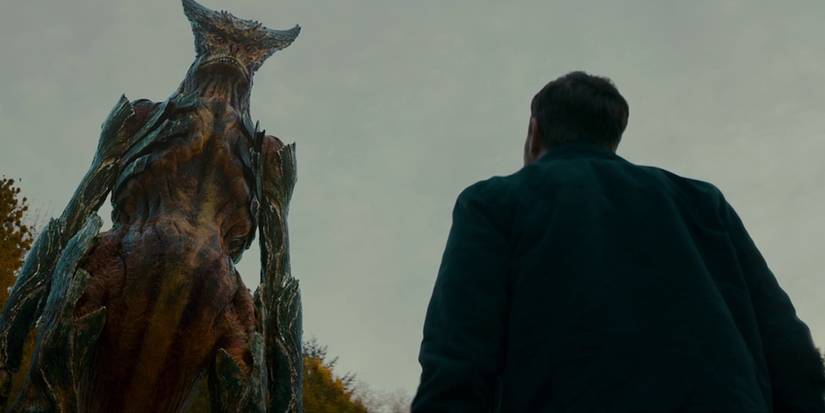A man looking at a giant monster approaching in the film Colossal