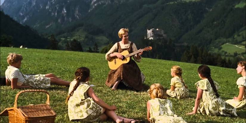 Maria plays guitar and sings surrounded by children in a meadow in The Sound of Music.