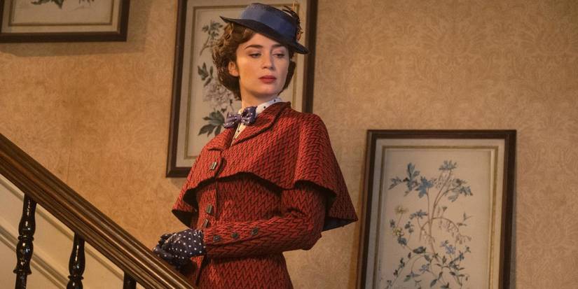 Emily Blunt as Mary Poppins with a haughty expression on a staircase in Mary Poppins Returns