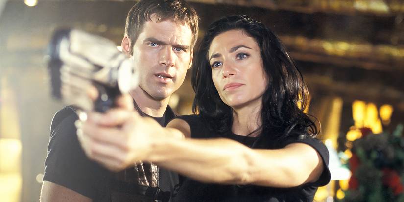 John standing next to Aeryn while she points a gun in the series Farscape.