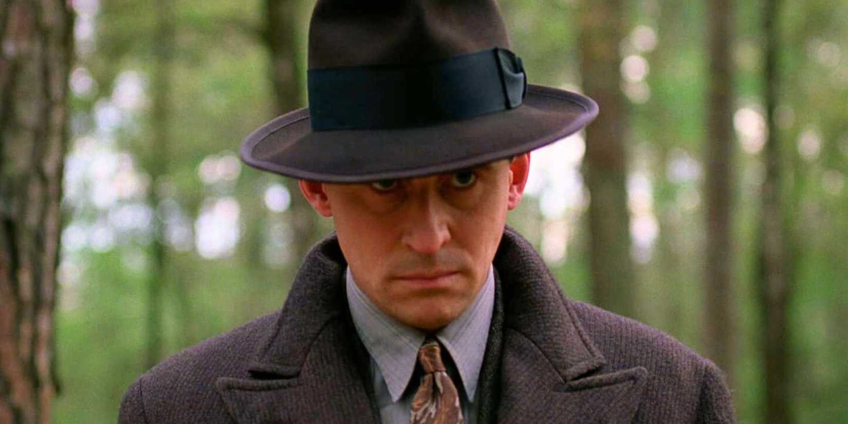 Gabriel Byrne standing alone in the woods peering up in Miller's Crossing (1990)