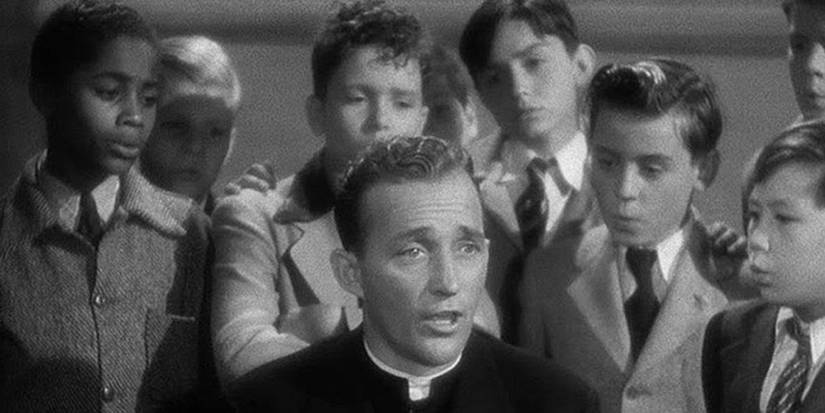 Bing Crosby as Father Chuck O'Malley surrounded by a group of boys in Going My Way