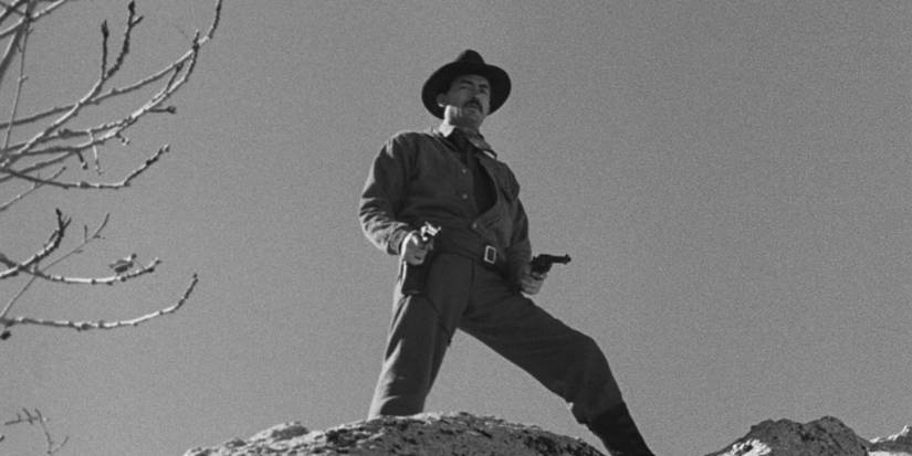 Gregory Peck atop a cliff with pistols drawn in The Gunfighter