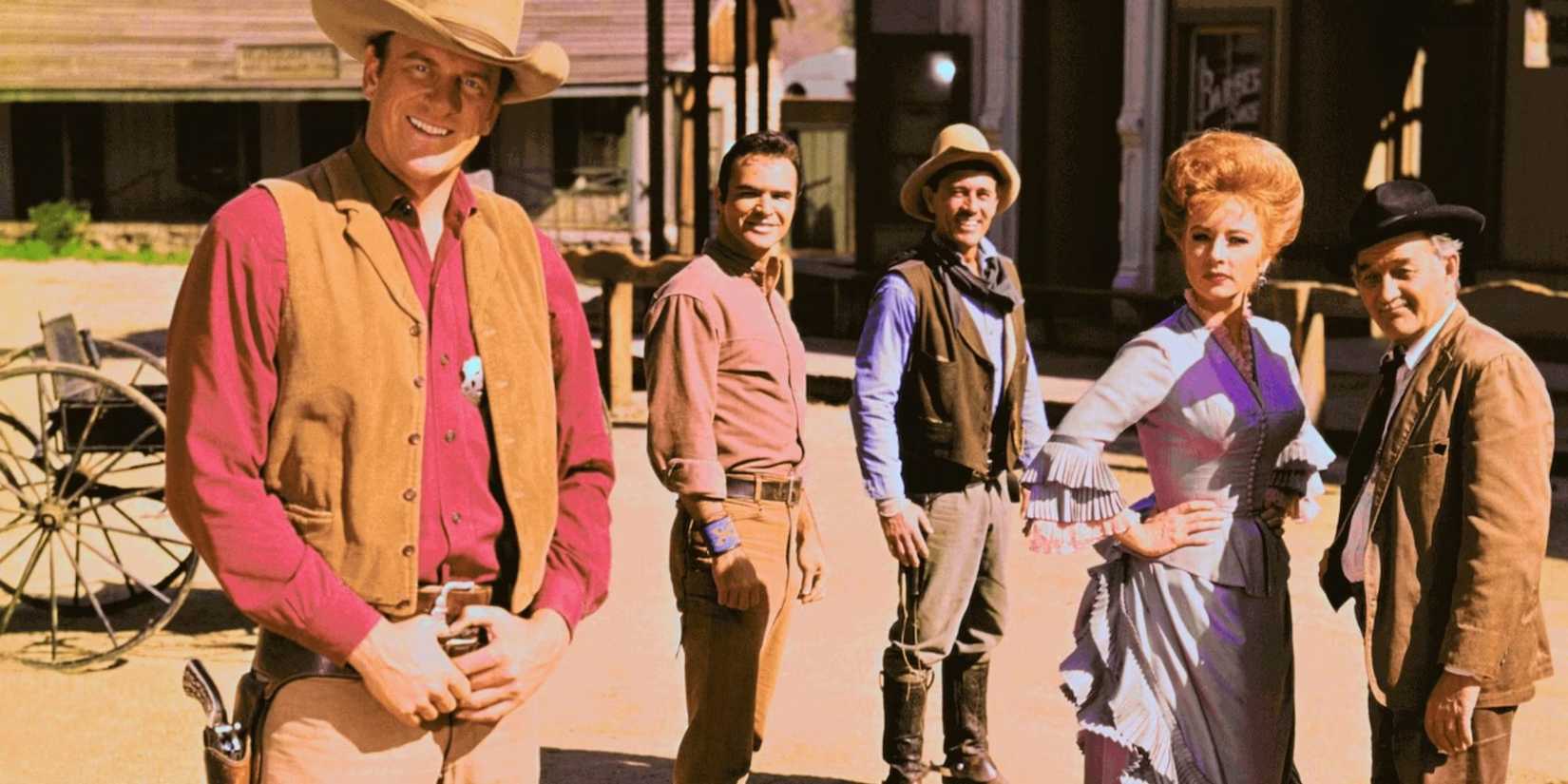 The cast of Gunsmoke in western attire outside looking at the camera.